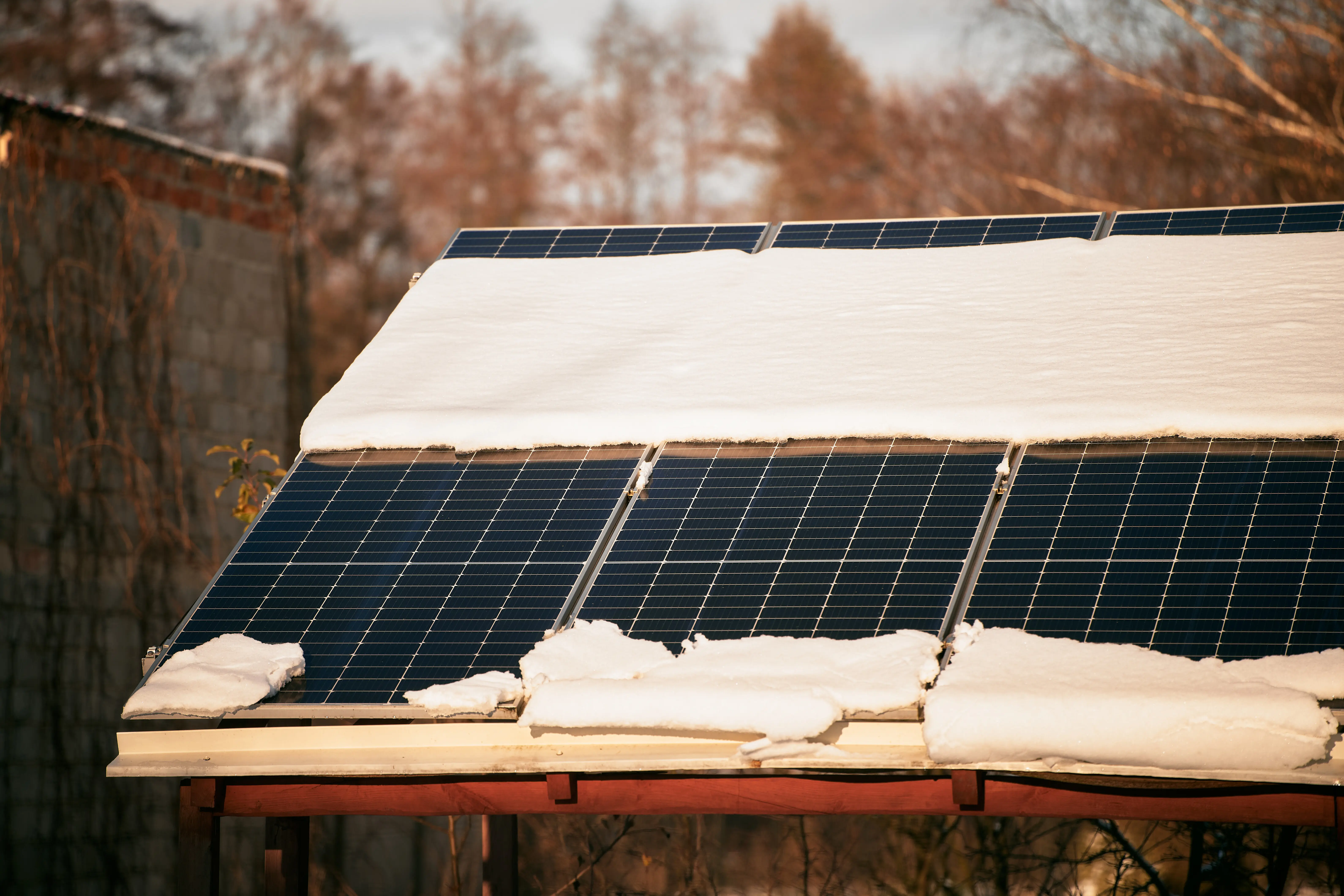 Schnee schmilzt von schneebedeckten Photovoltaikmodulen auf einem Hausdach, die zur Erzeugung nachhaltiger elektrischer Energie installiert sind – Konzept der geringen Effizienz erneuerbarer Elektrizität in den Klimazonen nördlicher Regionen.