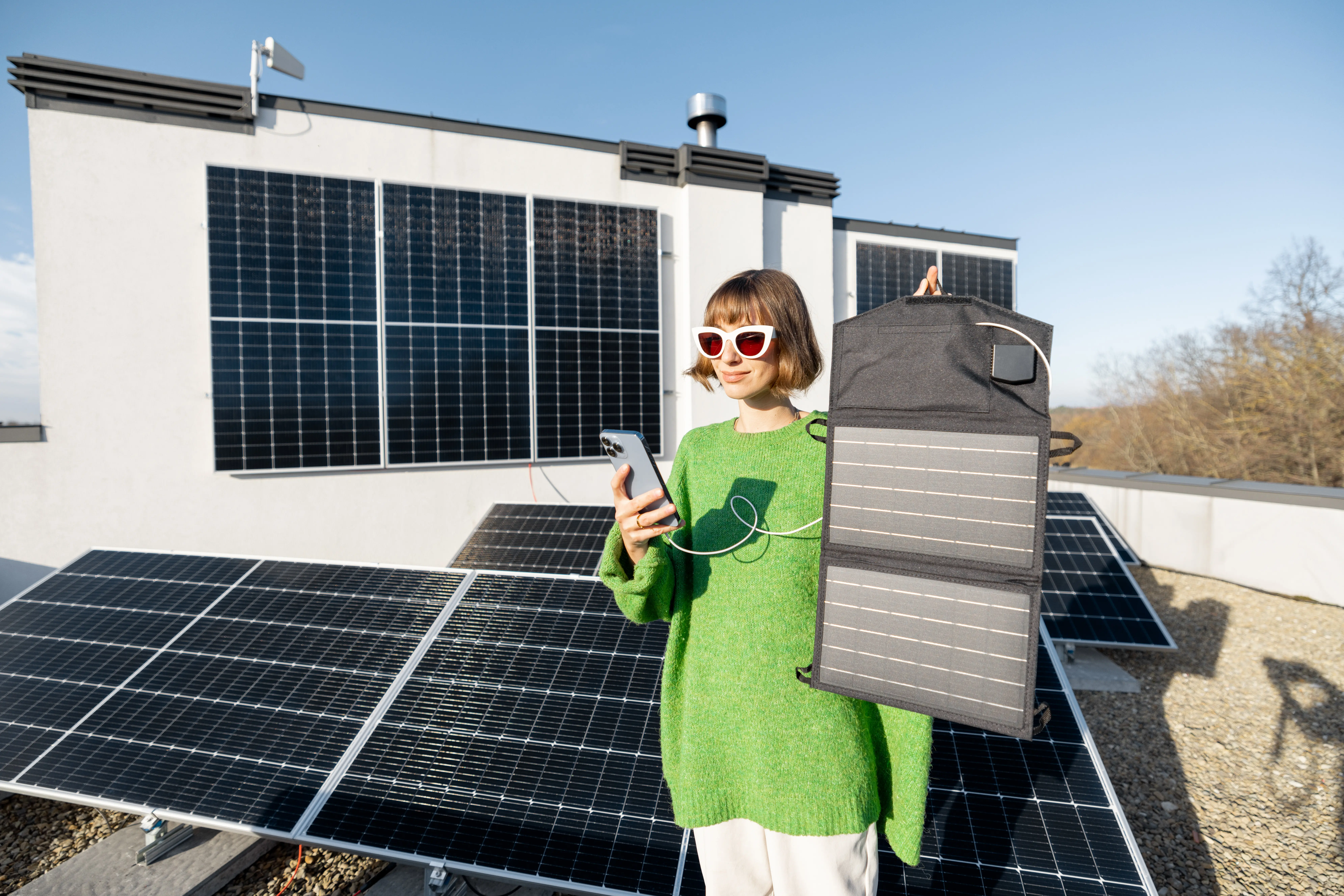 Eine Frau lädt ein Handy mit einem tragbaren Solarpanel auf.